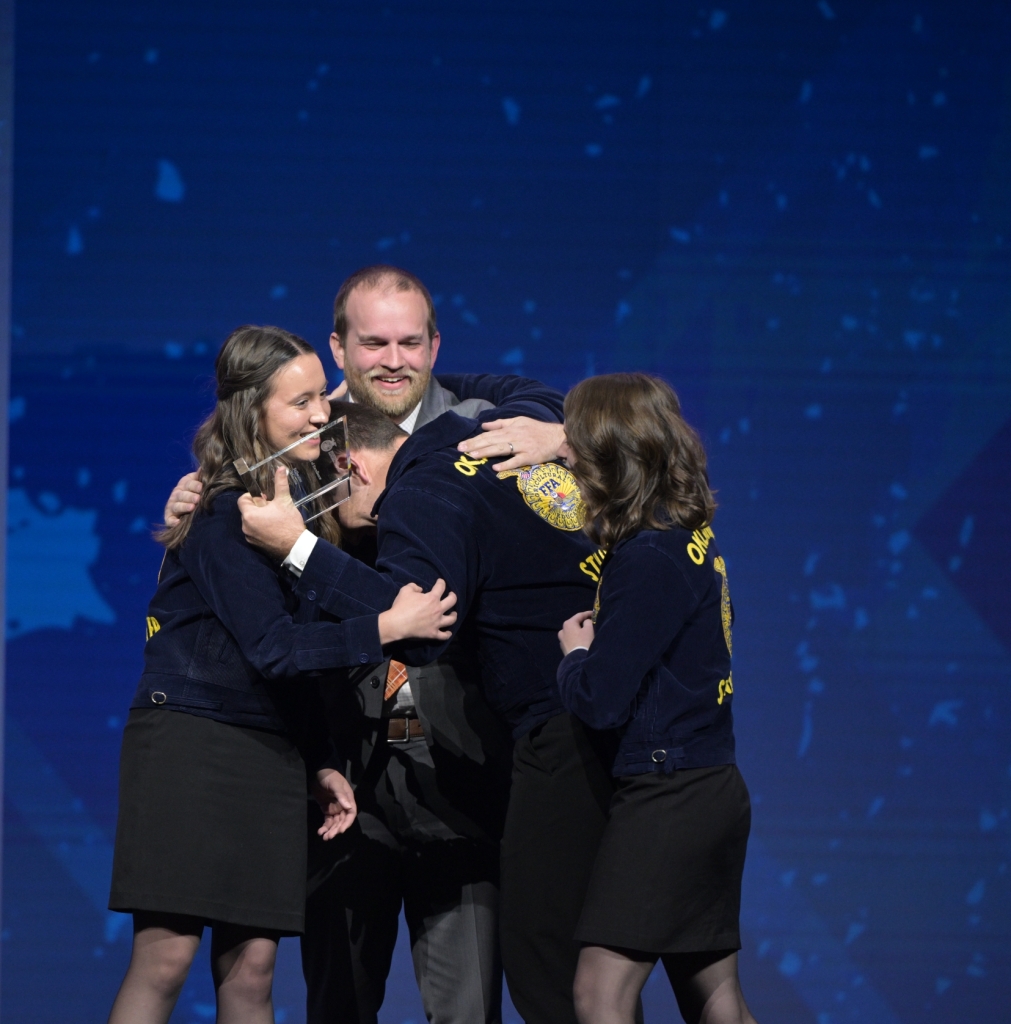 Stillwater FFA members and their advisor, Robby Branscum, react to being named the 2023 Model of Excellence on stage at convention.
