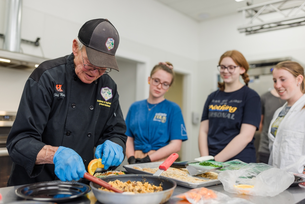 Hagerman FFA members prepare a dish with their teacher, Kirt Martin (left).