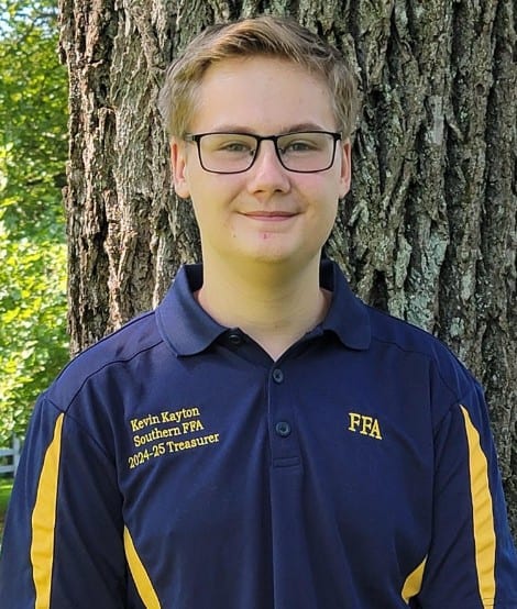 Kevin Kayton is shown posing in front of a tree with his newly acquired FFA officer polo.