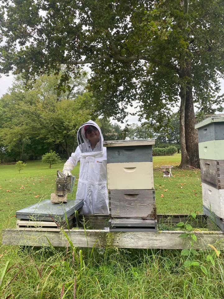 Channing Anderson in her bee suit checking the bees.