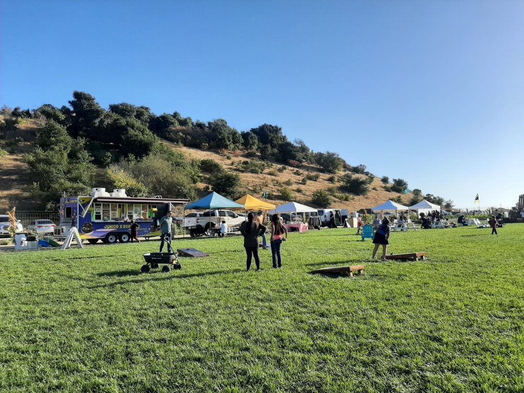 Salinas community members play lawn games on a patch of grass in front of a food truck and vendors at The Patch.