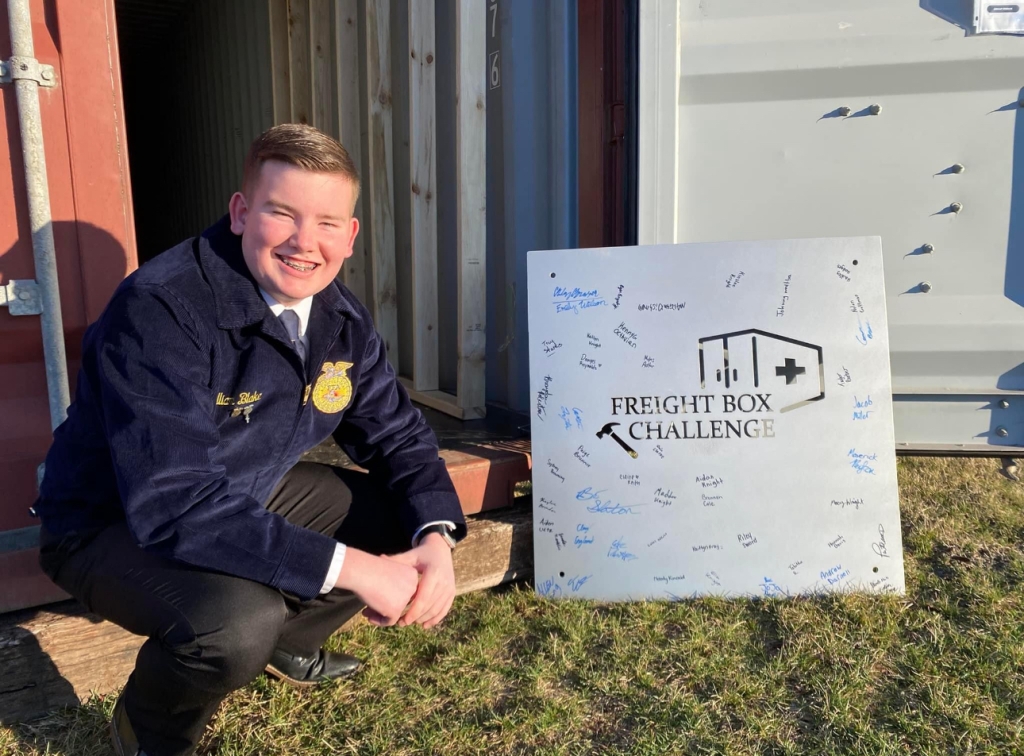 William Blake poses with the sign his chapter made for the project.