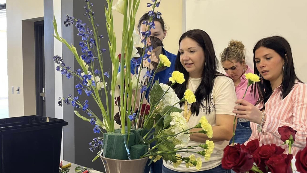 Sara Burke (center) leads her students through creating a floral arrangement.