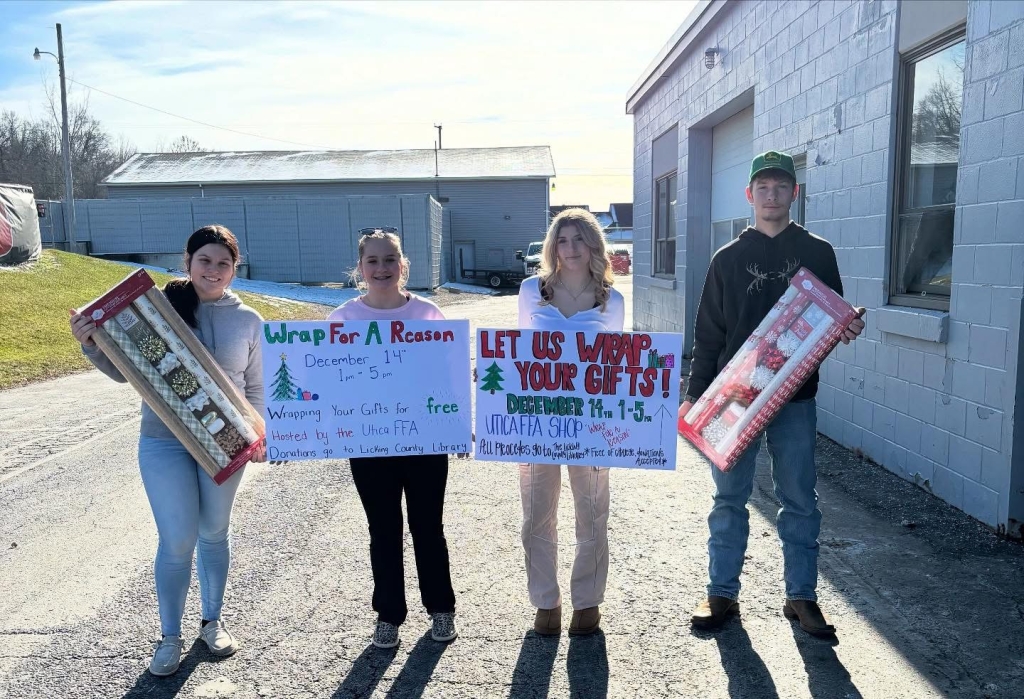 Lillian Layman (far left), Emmie Burgess (middle left), Ashley Teeters (middle right) and James Bebout (far right) hold signs for the Utica FFA Chapter’s Wrap for a Reason event.