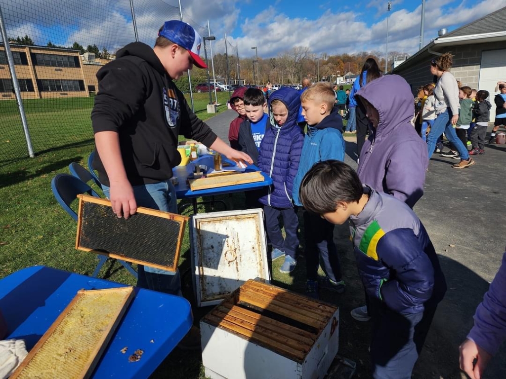 Penn Yan FFA Vice President Colt Walters teaches students about honey production.