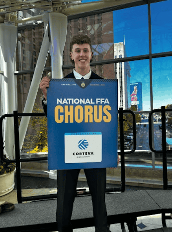 Evan Keppy poses for a photo with the National FFA Chorus banner during his week in Indianapolis.