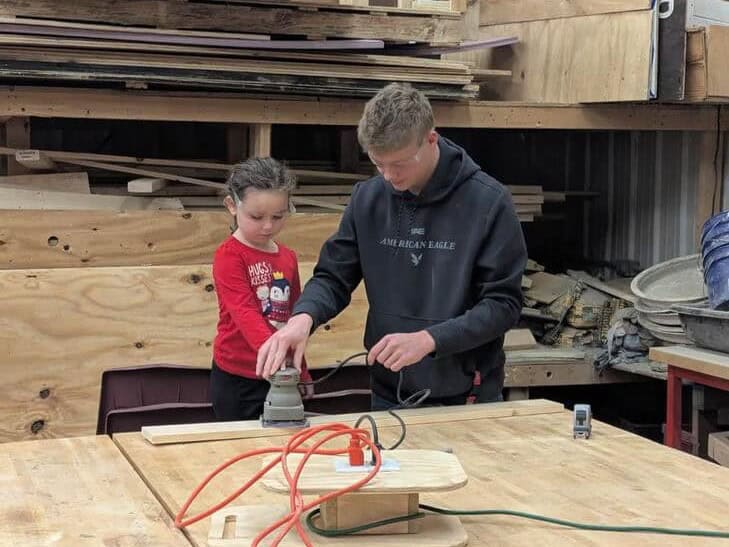 FFA member Peyton Lilly teaches a student how to properly develop her project while prioritizing safety.