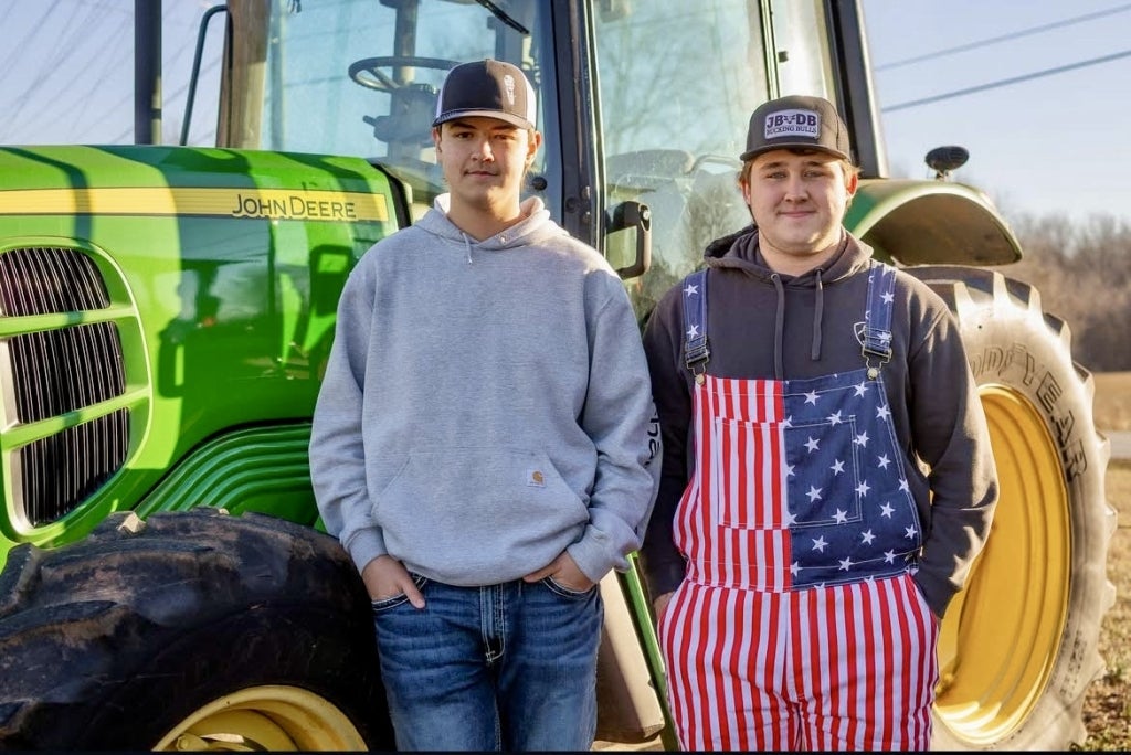 Dillan Mills (left) and Kaden Harris (right) stand in front of their tractor.