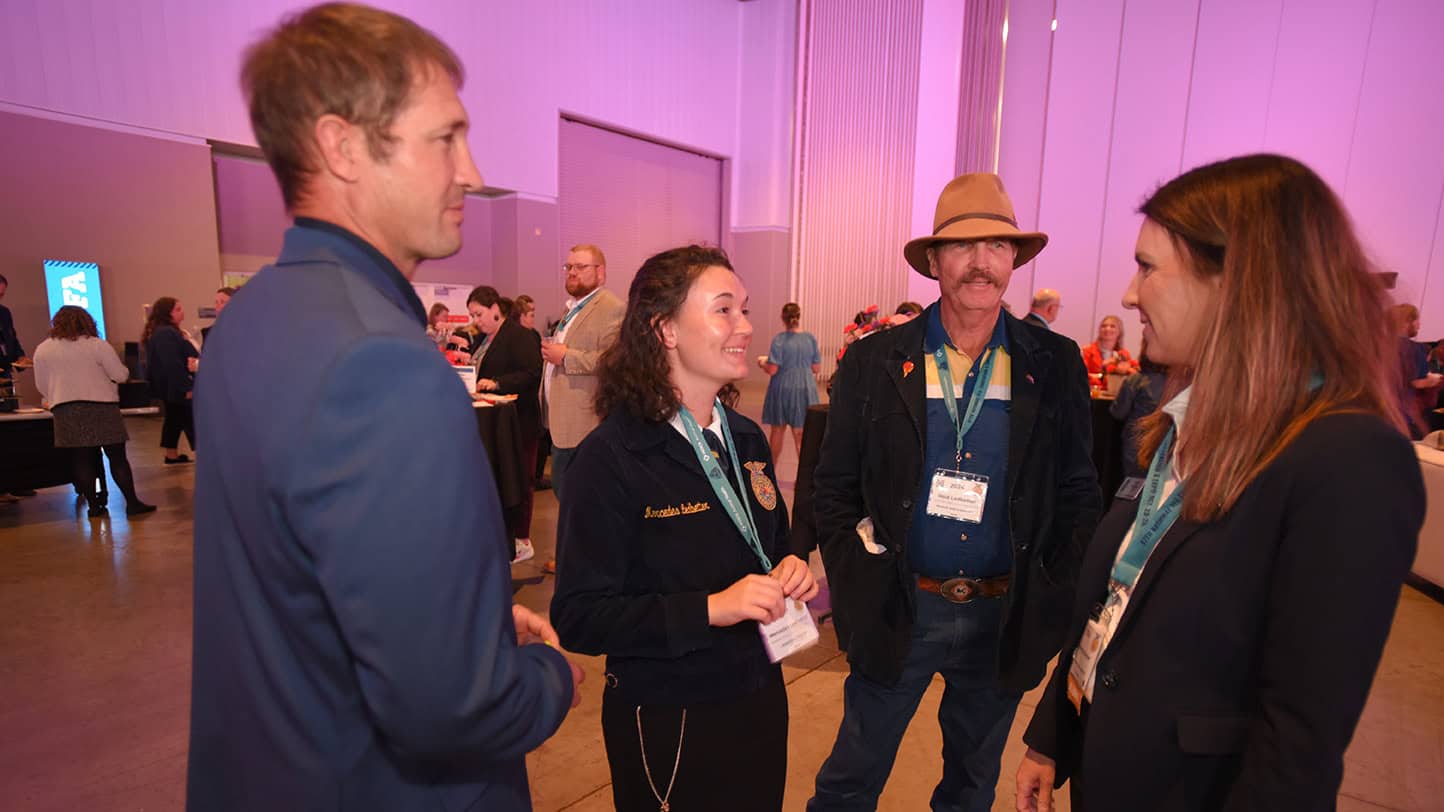 Four FFA Alumni talking at an event.