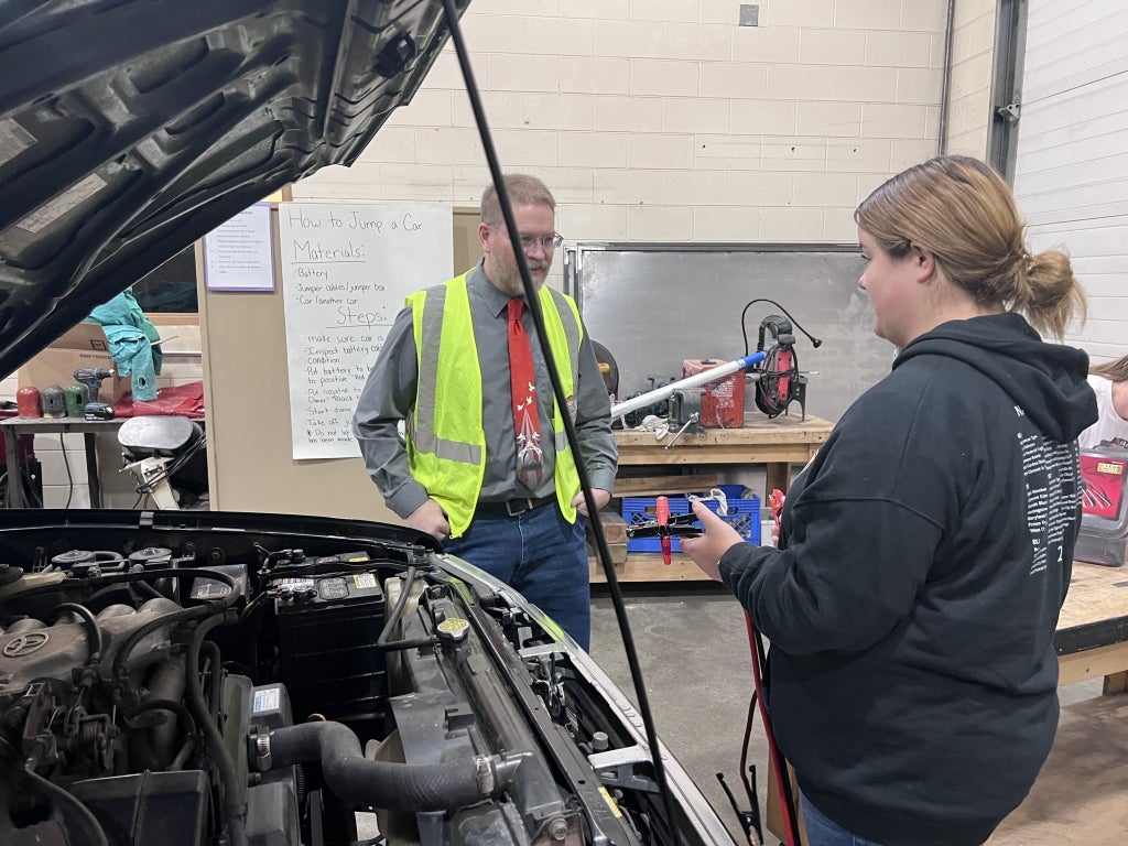 A SURVIVOR WEEK volunteer (left) teaches a Felicity-Franklin High School student (right) how to jump-start a car. Photo courtesy of Holly Jennings.