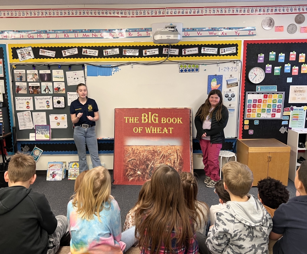 Kaydance Meikle (left) uses “The Big Book of Wheat” to teach the second grade students.