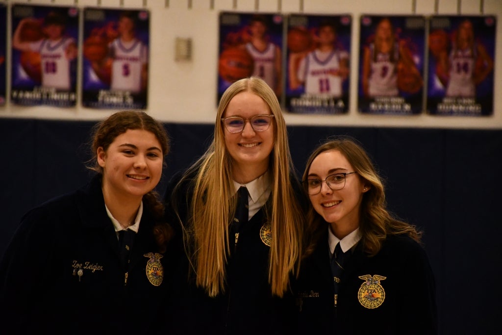 Penn Yan FFA Student Advisor Zoe Ziegler (left), Historian Bailey Kennedy (middle) and Reporter Rachel Dann (right) smile during the school-wide assembly.