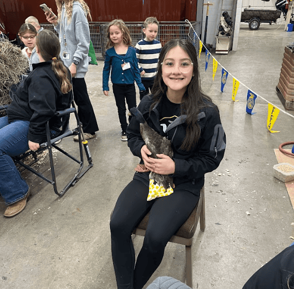 Selena Fuentes smiles with her chicken at the 2024 Olney FFA petting zoo.